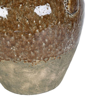 Close-up of a ceramic vase or planter with a rustic glazed finish, showing a mottled brown upper section and a matte gray-green lower section on a white background.