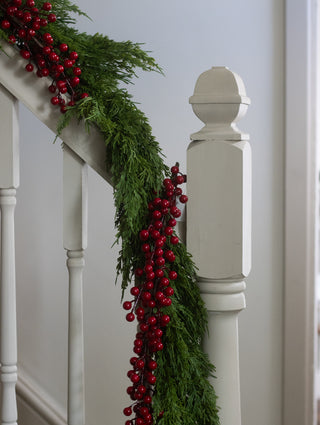 Crimson berry garland wrapped around a newel post with greenery