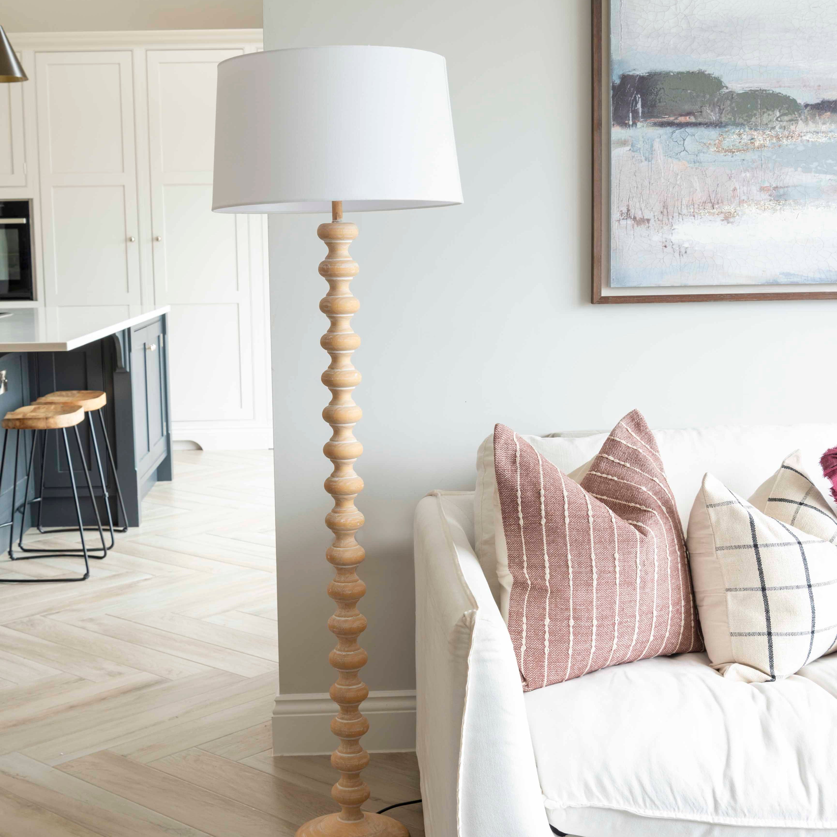 A stunning floor lamp in a beautiful turned pale wood complete with off white linen shade.