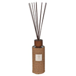 Reed diffuser with woven design and wooden top on a white background