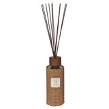 Reed diffuser with woven design and wooden top on a white background