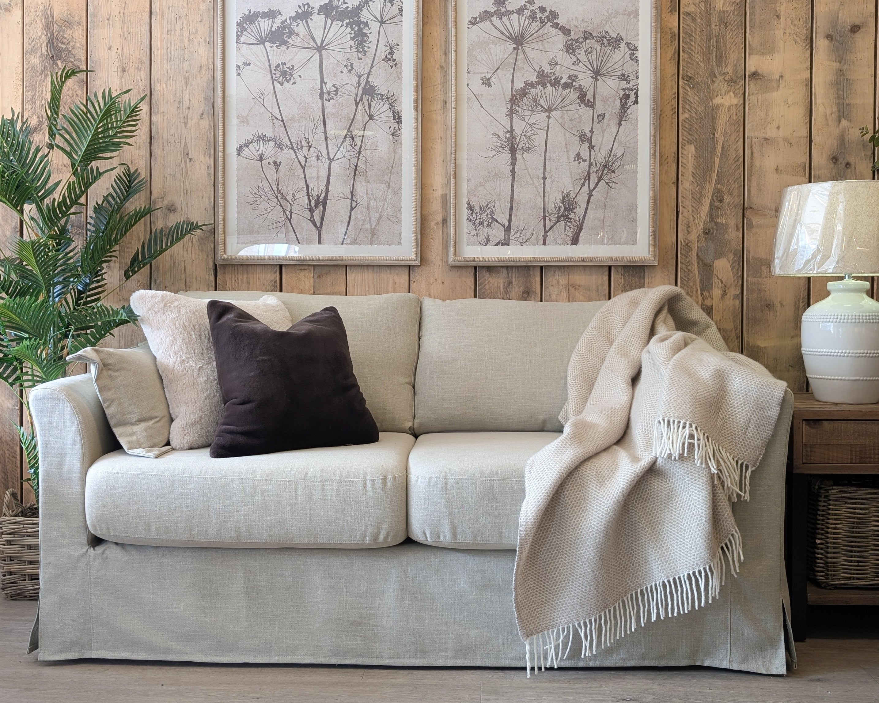 Carmel neutral loose cover sofa in Keystone Earth fabric with plush cushions, soft throw, and rustic wood backdrop