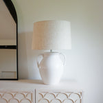 "White ceramic urn table lamp with linen shade on sideboard