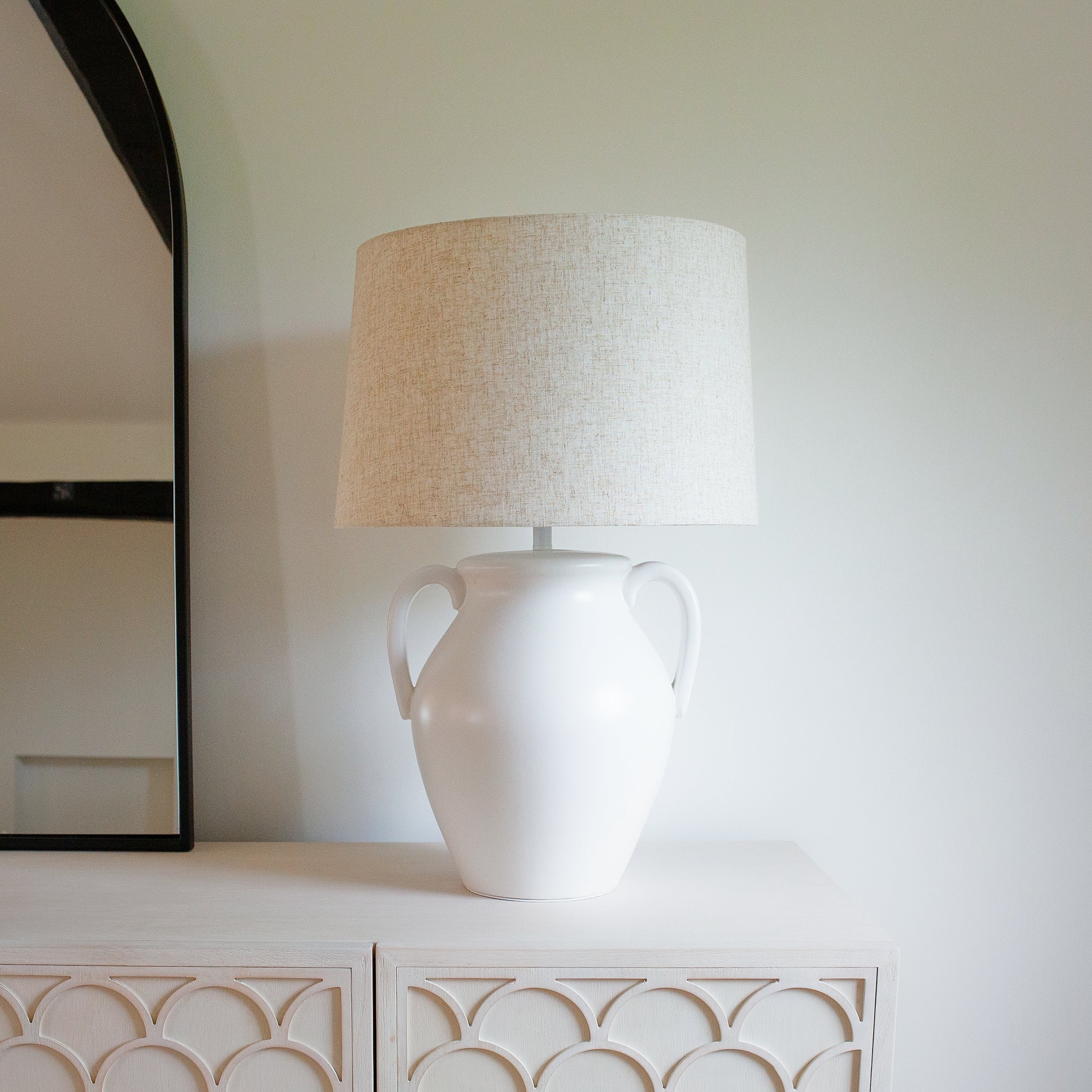 "White ceramic urn table lamp with linen shade on sideboard