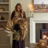 a premium autumnal wreath held my woman by fire in cosy living room
