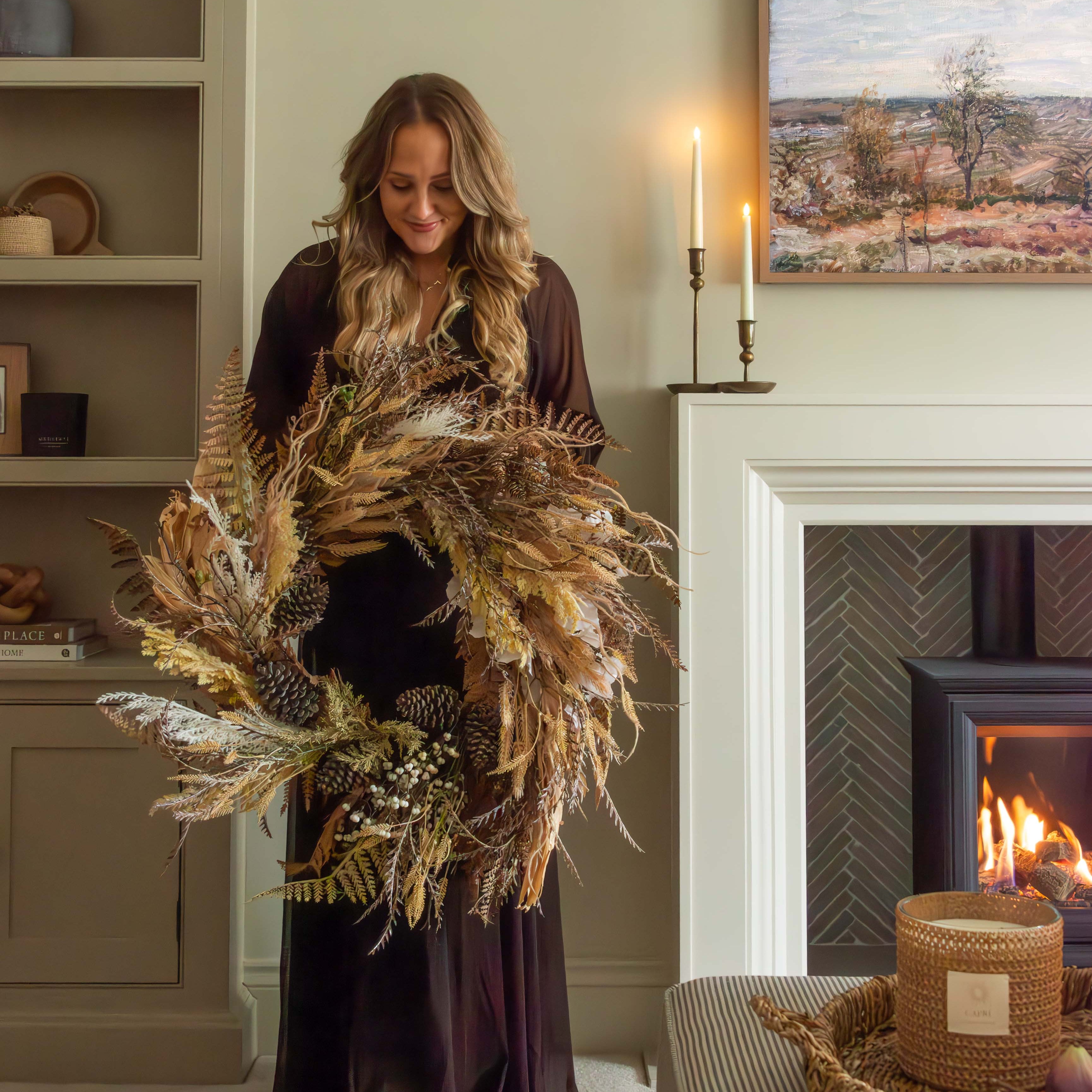 a premium autumnal wreath held my woman by fire in cosy living room