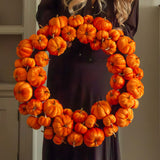 Woman holding a large orange pumpkin wreath in a cosy living room. close up detail
