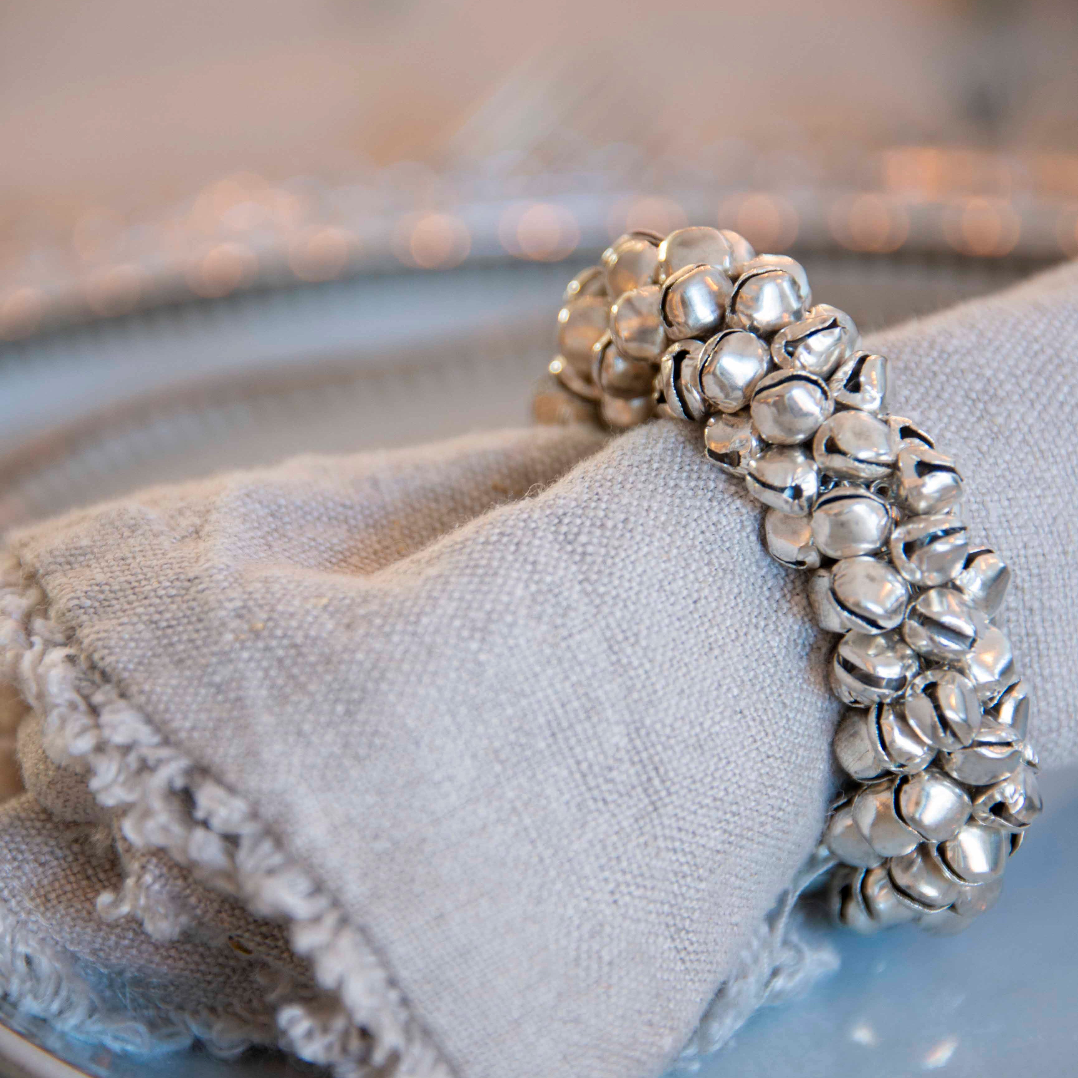 Close-up of silver bell napkin ring on cloth napkin