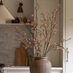 Charles Ted Faux Dusky Pink Blossom Spray Stem in brown vase on marble countertop