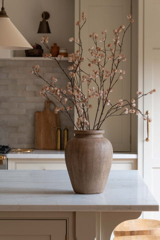Blossom stems leaning from a dark glazed vessel