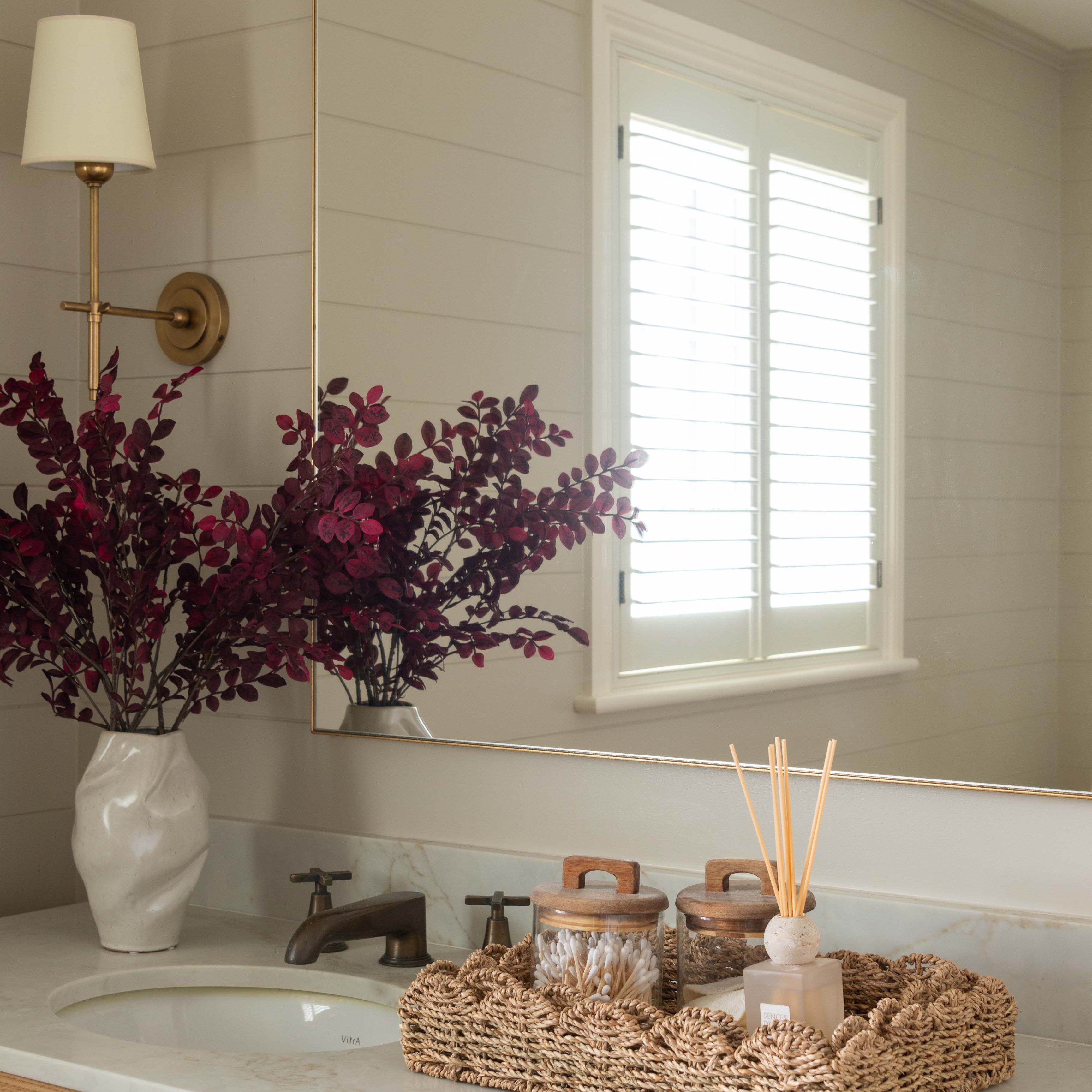 Bathroom vanity with a mirror, sink, and decorative items.
