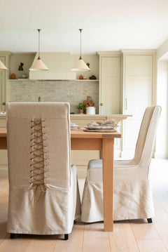  chair features a beautifully tailored loose linen slipcover in a natural beige hue, accented with a charming corset-style lace-up back for added visual interest and secure fit.