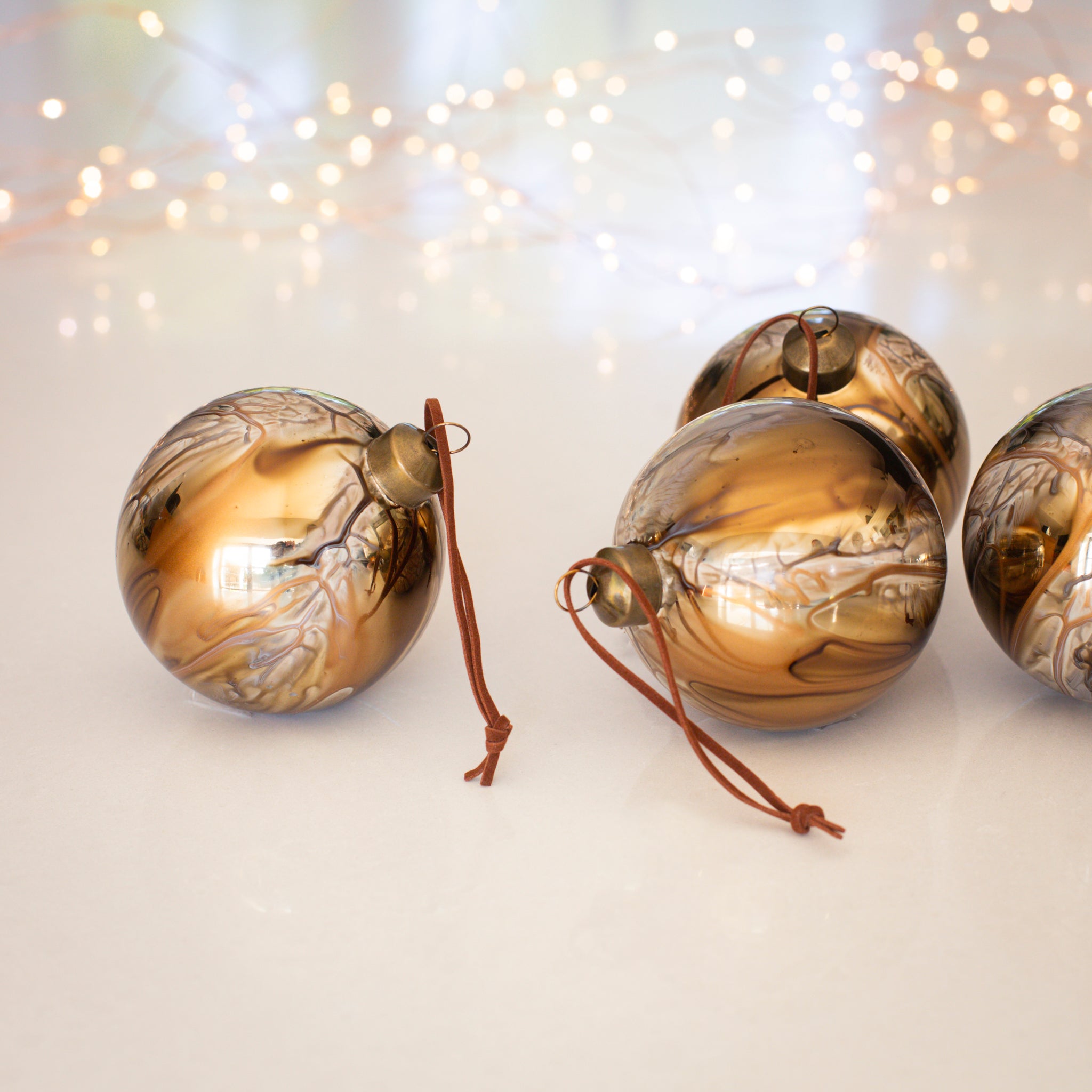 Charles Ted Marble Glass Baubles in bronze and cream tones displayed on a white surface