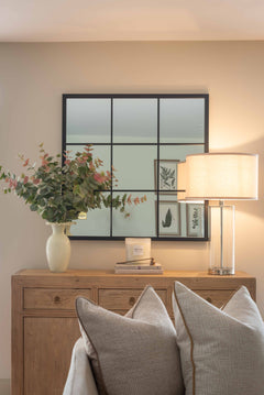 Minimalist bedside lamp with clear glass base and drum shade