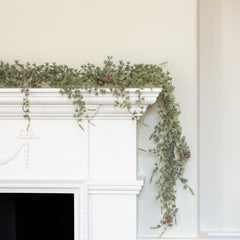 Charles Ted Pine Garland with frosted greenery and pinecones displayed across a white mantel and held for styling