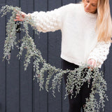Charles Ted Pine Garland with frosted greenery and pinecones held by woman in a white jumper