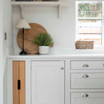 The breadboard is propped upright on a counter behind a potted plant, adding a stunning display piece to this kitchen