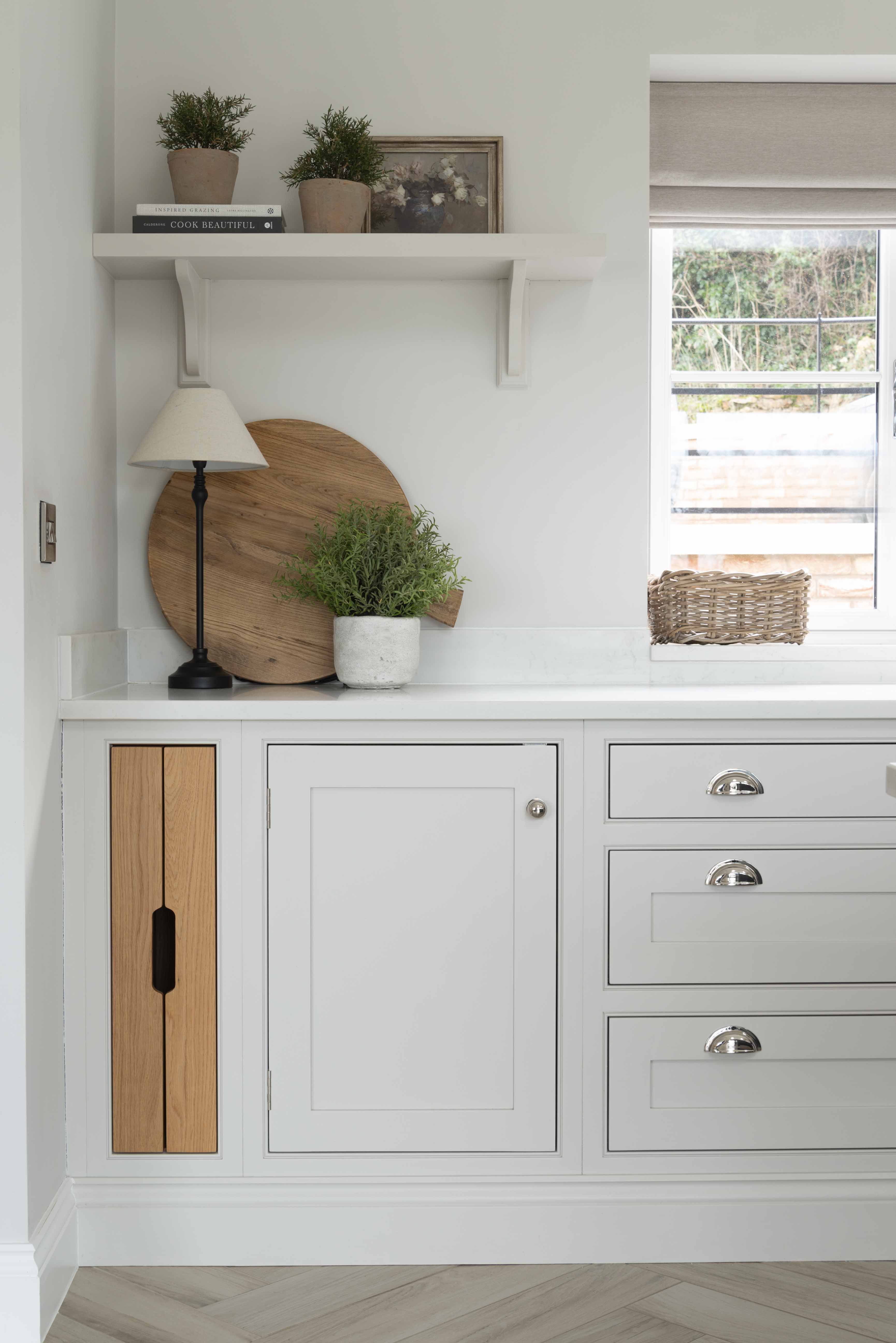 The breadboard is propped upright on a counter behind a potted plant, adding a stunning display piece to this kitchen
