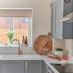 Modern kitchen with gray cabinets, white countertop, and wooden cutting board.