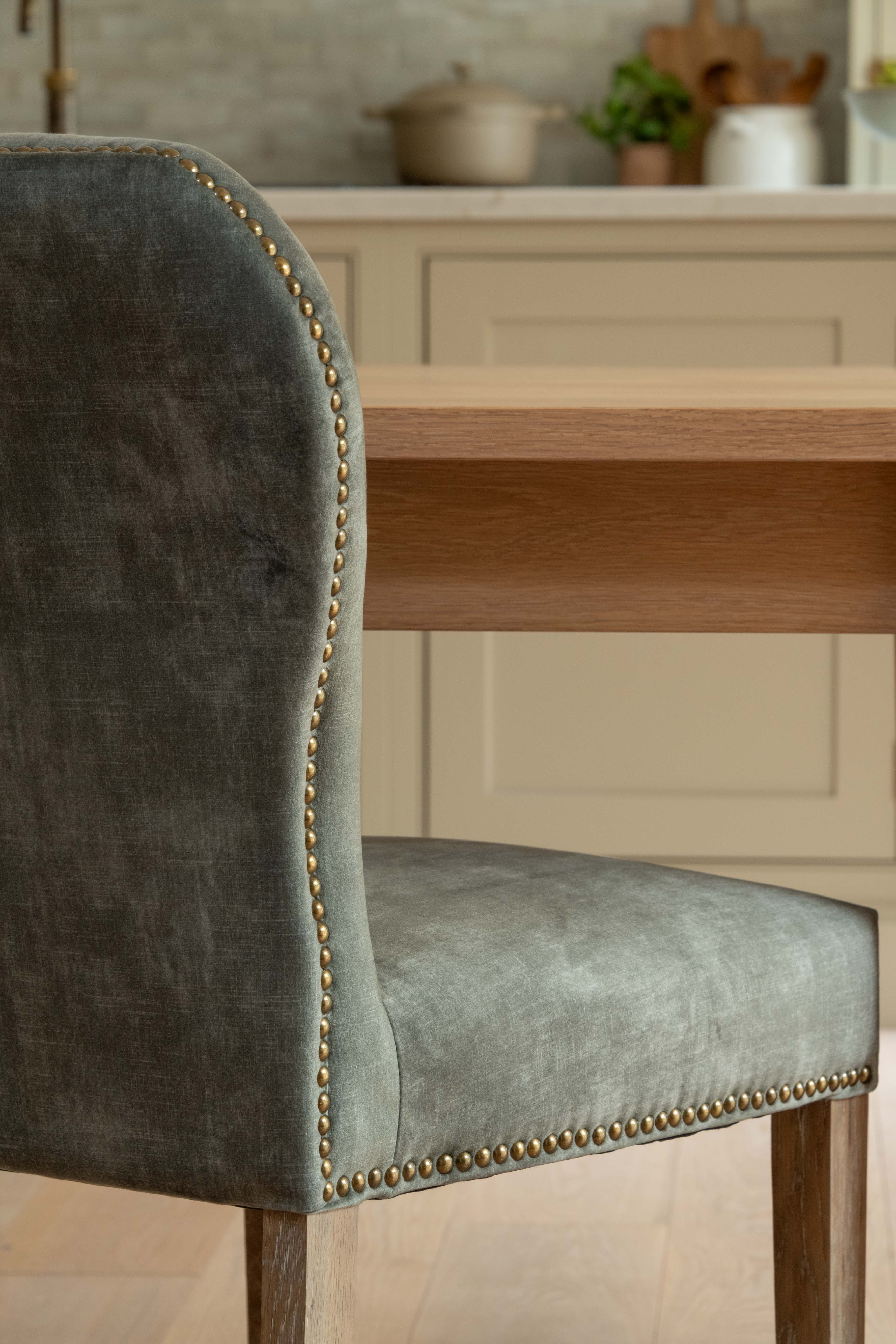 Green velvet chair with nailhead trim in a kitchen setting