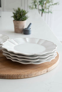 Charles Ted white scalloped dinner plates stacked on wooden board