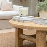 Wooden coffee table with books and a candle in a living room setting