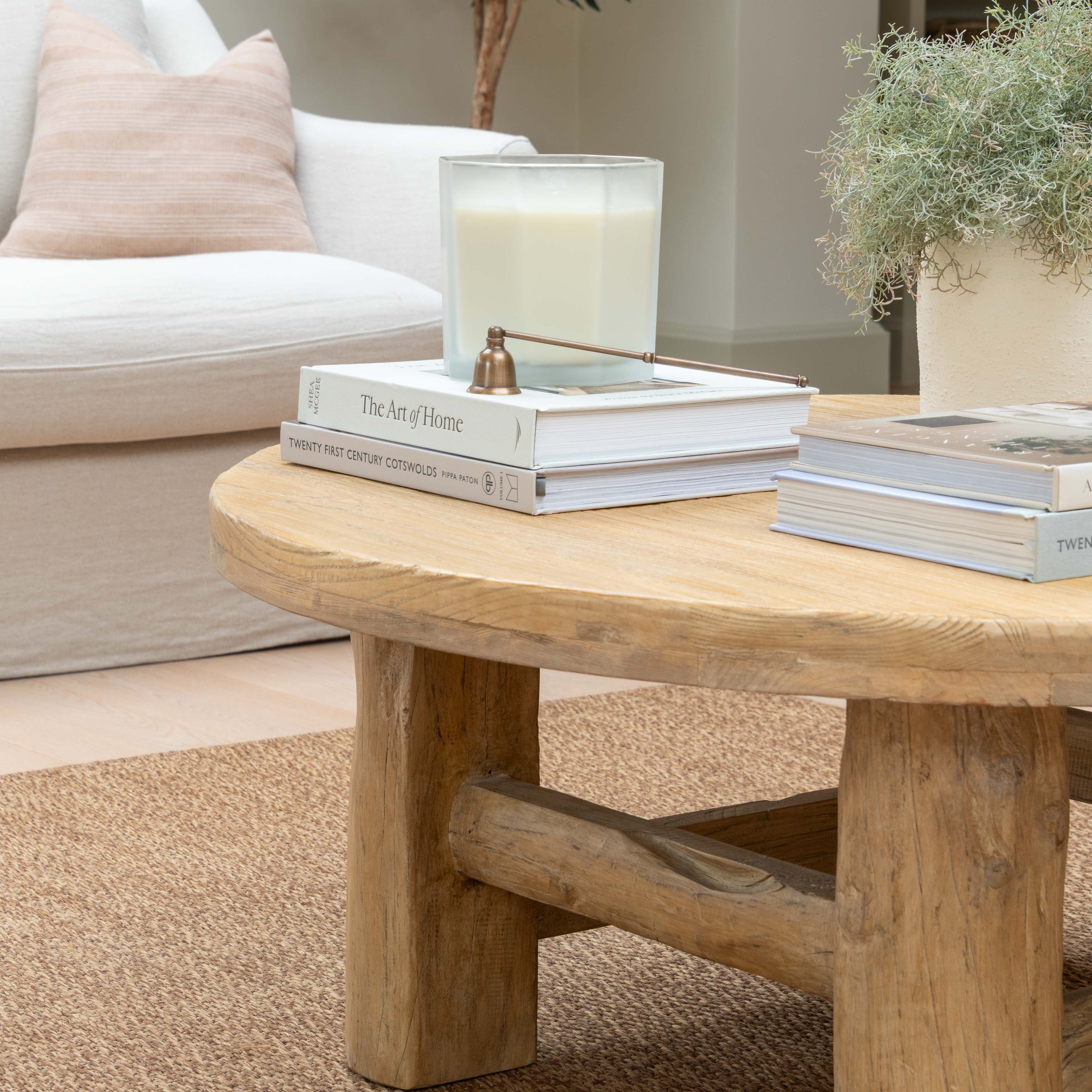 Wooden coffee table with books and a candle in a living room setting