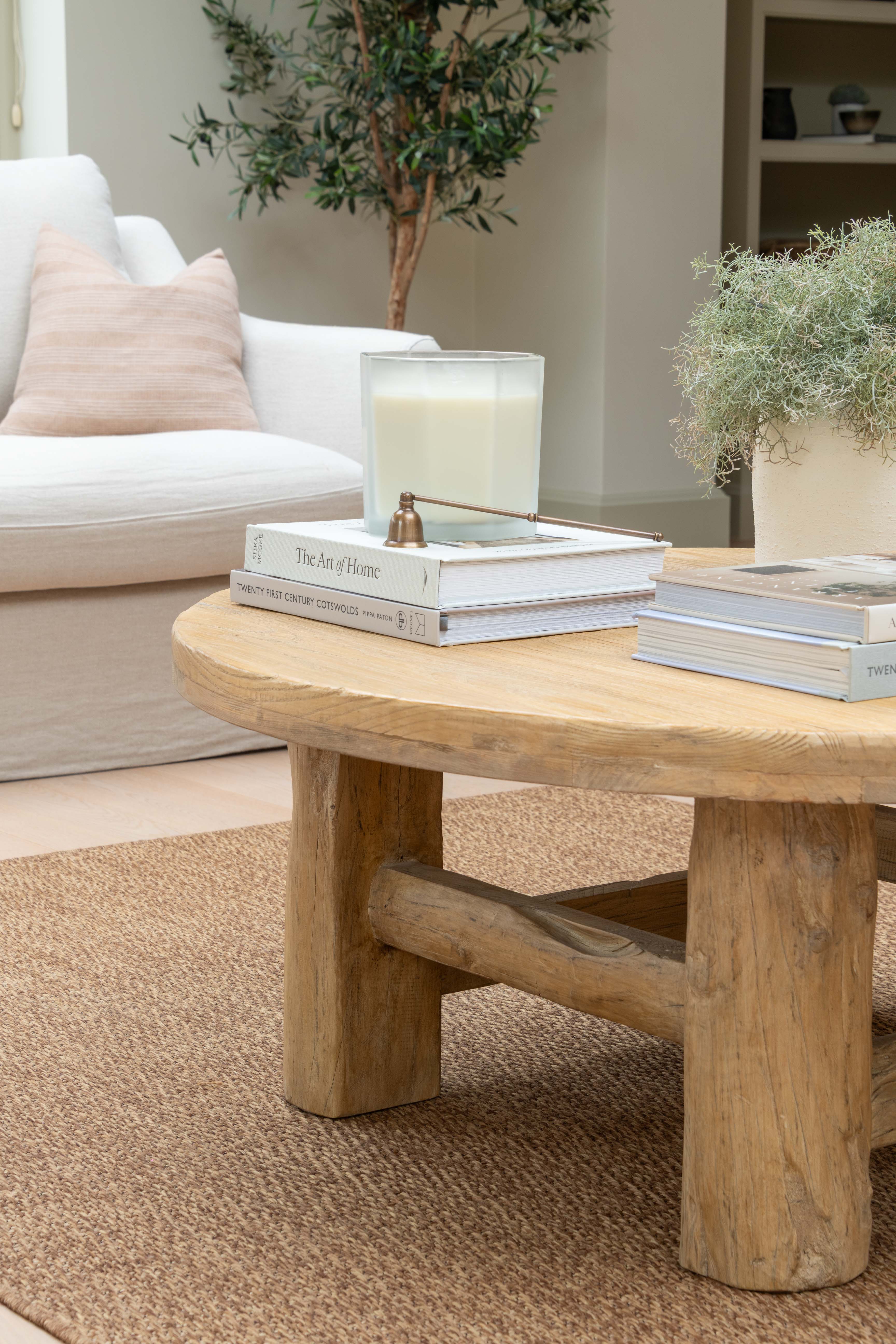 Wooden coffee table with books and a candle in a living room setting