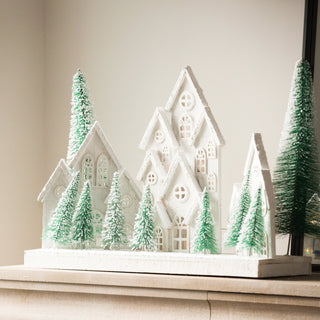 Snowy white Christmas village houses among frosted evergreen trees