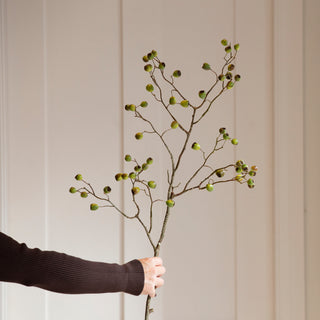 Large faux berry eucalyptus stem held against a panelled wall