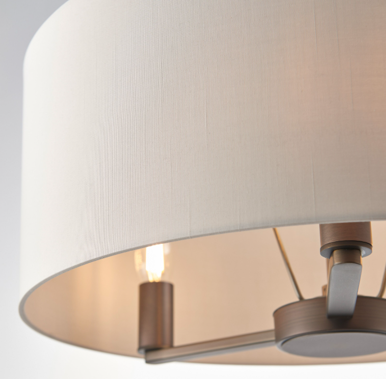 Close-up of a ceiling light fixture with a white lampshade and metallic fixtures.