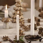 White candles tied with brown velvet ribbon on holiday table setting