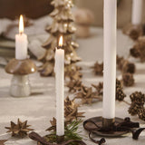 White candles tied with brown velvet ribbon on holiday table setting