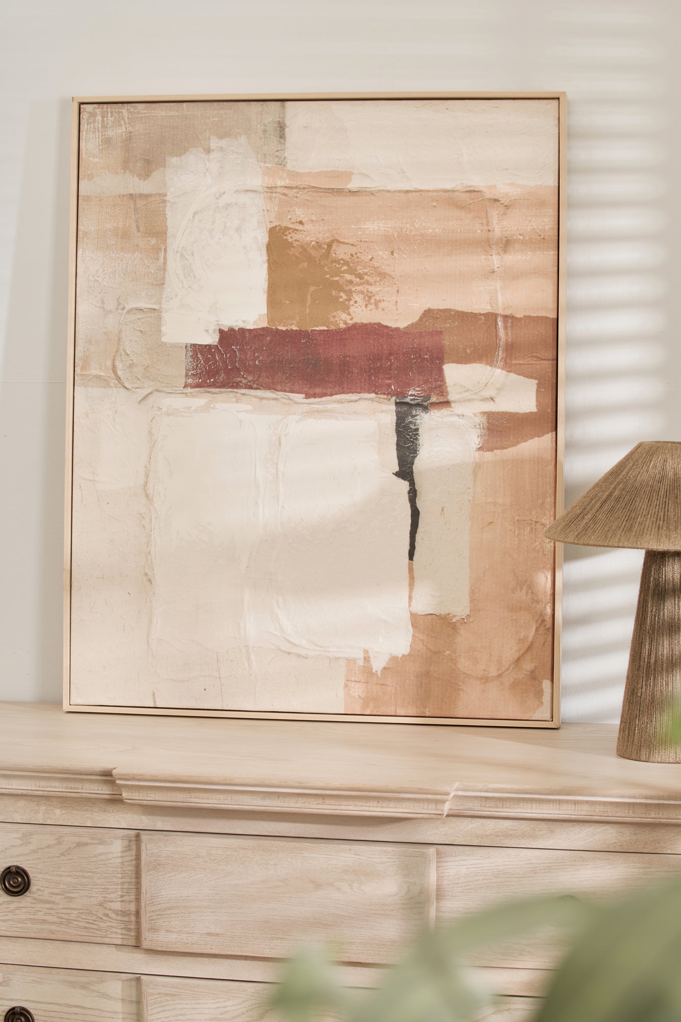 Abstract wall art styled on a light wood console with neutral home decor