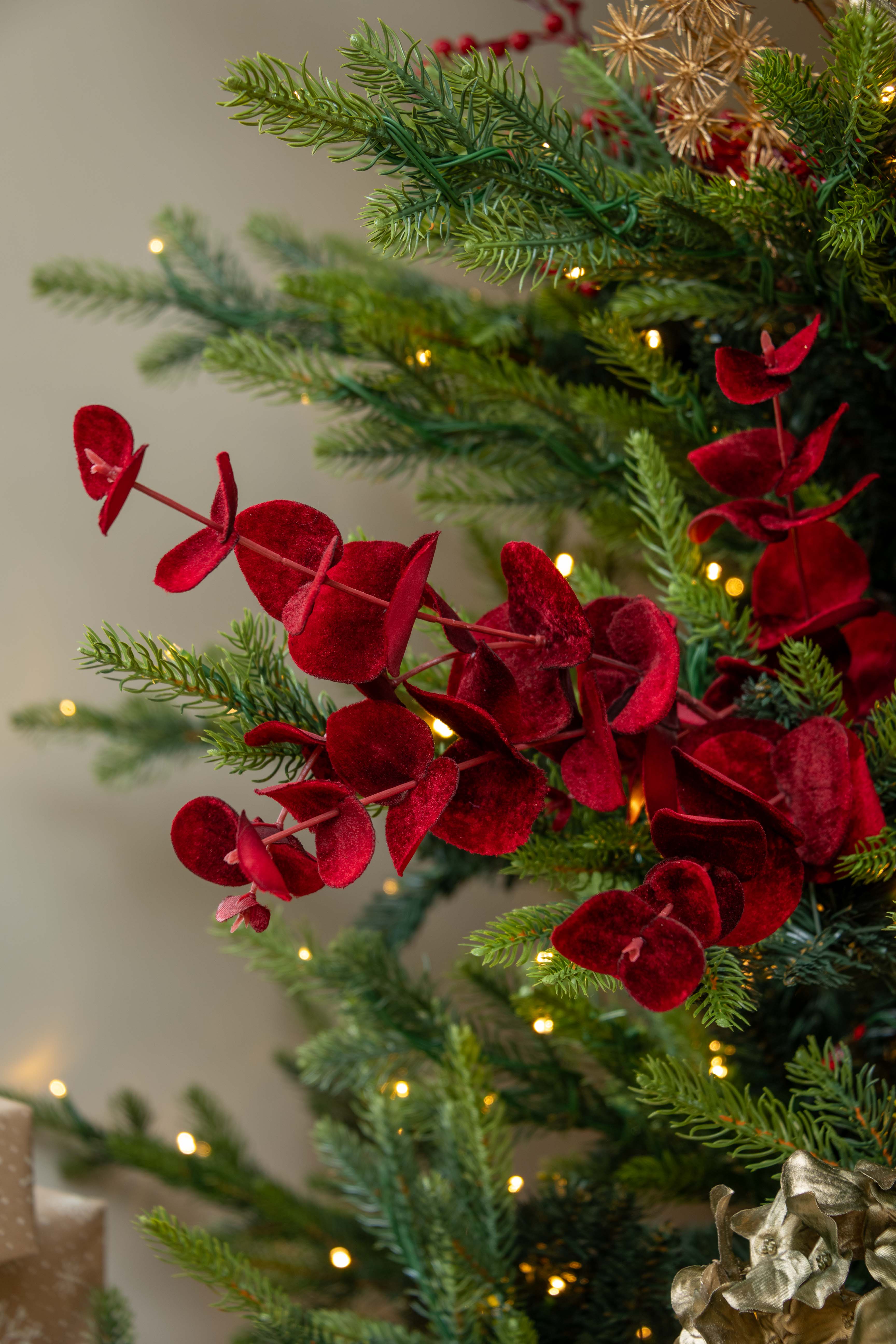 Decorative red flowers on a Christmas tree with lights in the background