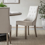 Button tufted linen dining chair with stud detailing and wooden legs in a modern dining room