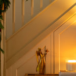 Decorative angel figure on a table with a candle next to a staircase