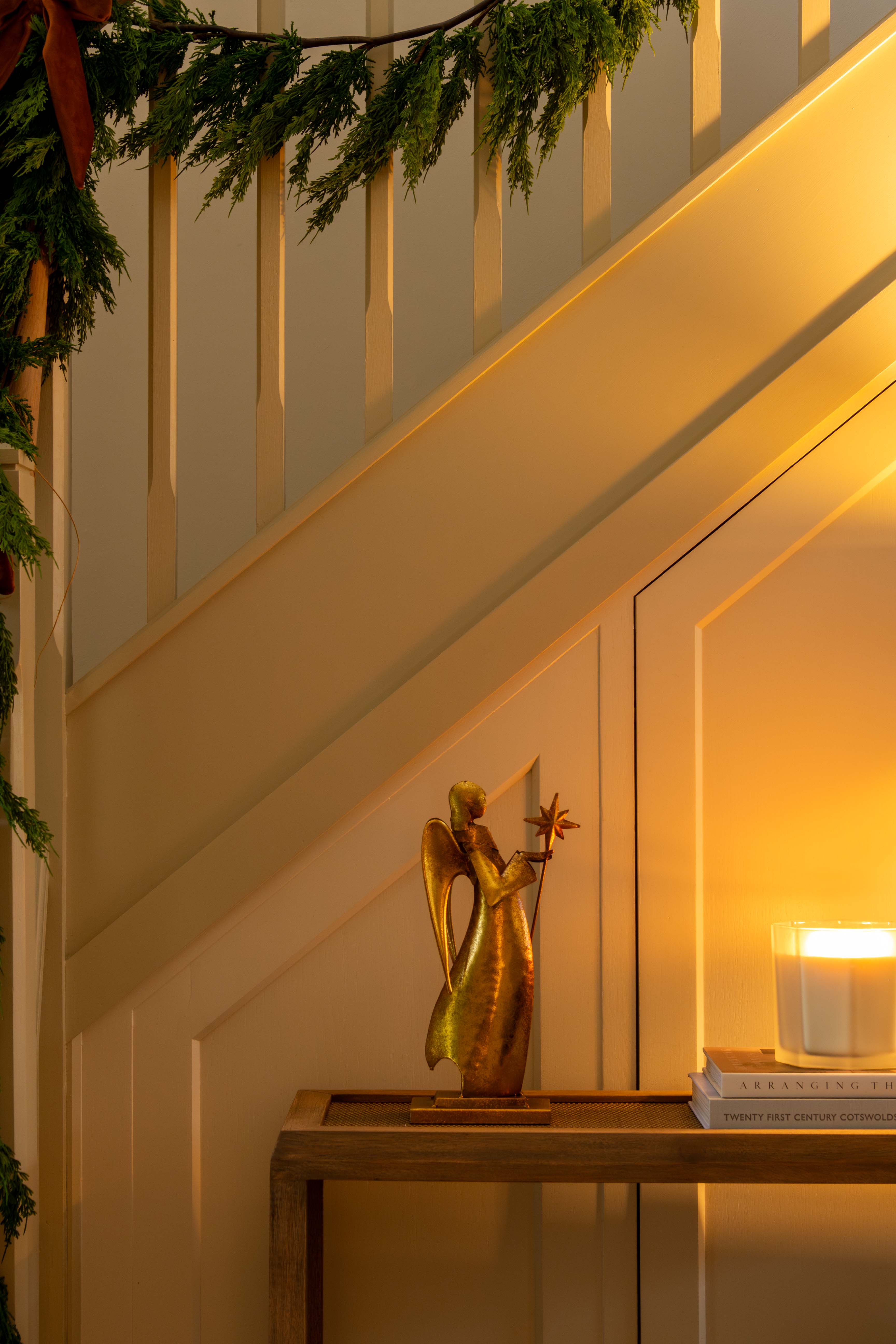 Decorative angel figure on a table with a candle next to a staircase
