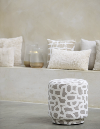 Patterned ottoman in front of a beige sofa with cushions