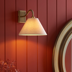 Dunston Antique Brass Wall Light illuminated against red wall