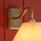 Curved antique brass arm and rectangular backplate of Dunston Wall Light