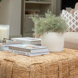 Living room with a woven ottoman, books, and a candle.