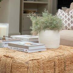 Living room with a woven ottoman, books, and a candle.