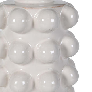 Close-up of the Eldon lamp's glossy white ceramic base, showing the rows of fully-rounded bobble texture and the highlights catching across the glaze