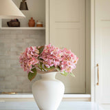 Bring effortless charm to your space with this beautifully crafted faux pink hydrangea, sold individually for versatile styling. Featuring lush, lifelike petals in soft blush tones and realistic green leaves, this artificial stem adds a delicate, romantic touch to any interior arrangement. Whether styled in a vase on your kitchen island, as shown, or combined with other stems for a fuller bouquet, it offers lasting beauty without maintenance.

Perfect for home décor, weddings, or gifting, this faux pink hyd