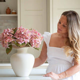 Bring effortless charm to your space with this beautifully crafted faux pink hydrangea, sold individually for versatile styling. Featuring lush, lifelike petals in soft blush tones and realistic green leaves, this artificial stem adds a delicate, romantic touch to any interior arrangement. Whether styled in a vase on your kitchen island, as shown, or combined with other stems for a fuller bouquet, it offers lasting beauty without maintenance.

Perfect for home décor, weddings, or gifting, this faux pink hyd