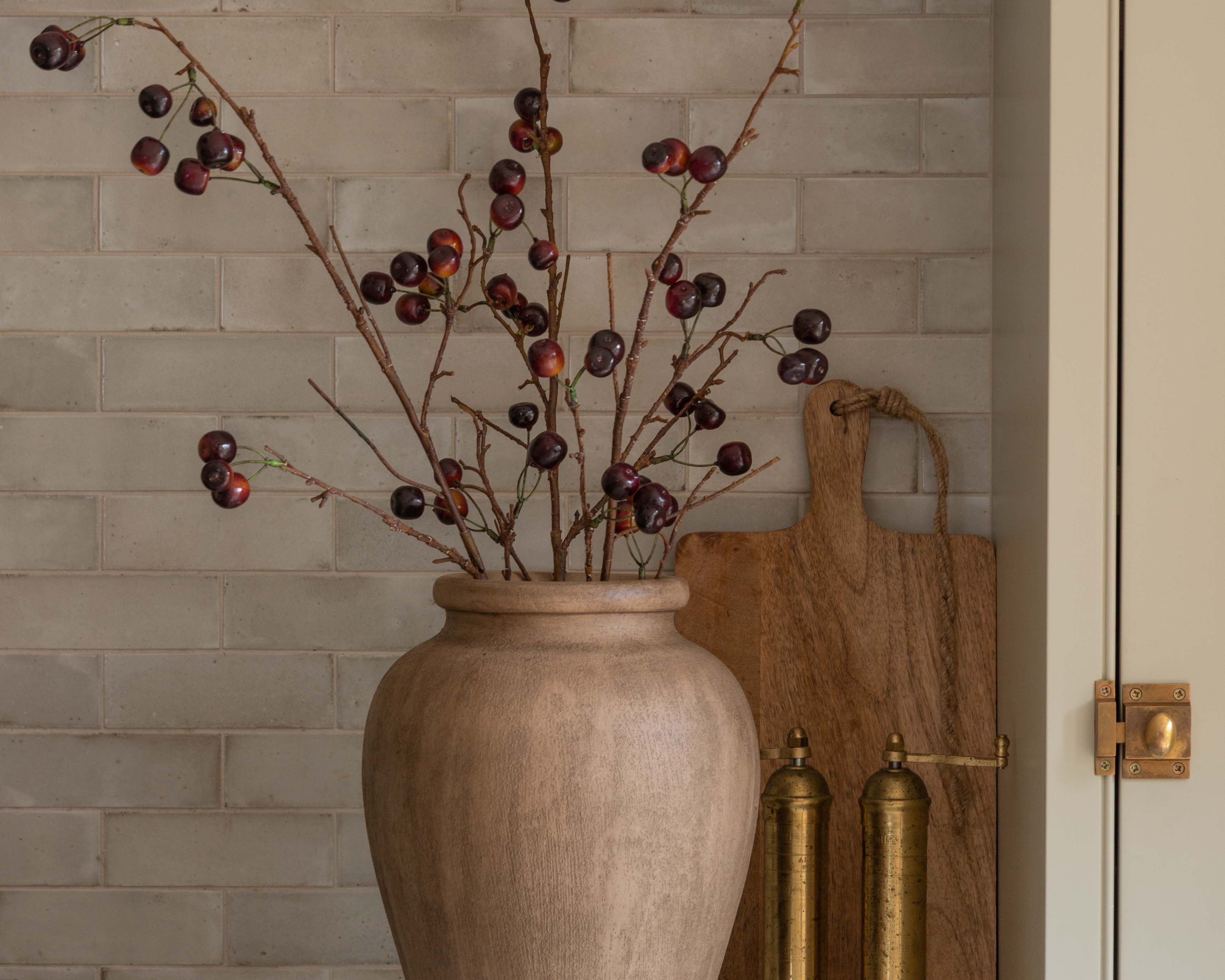 Charles Ted Faux Cherry Spray in a rustic vase styled against a tiled kitchen backsplash