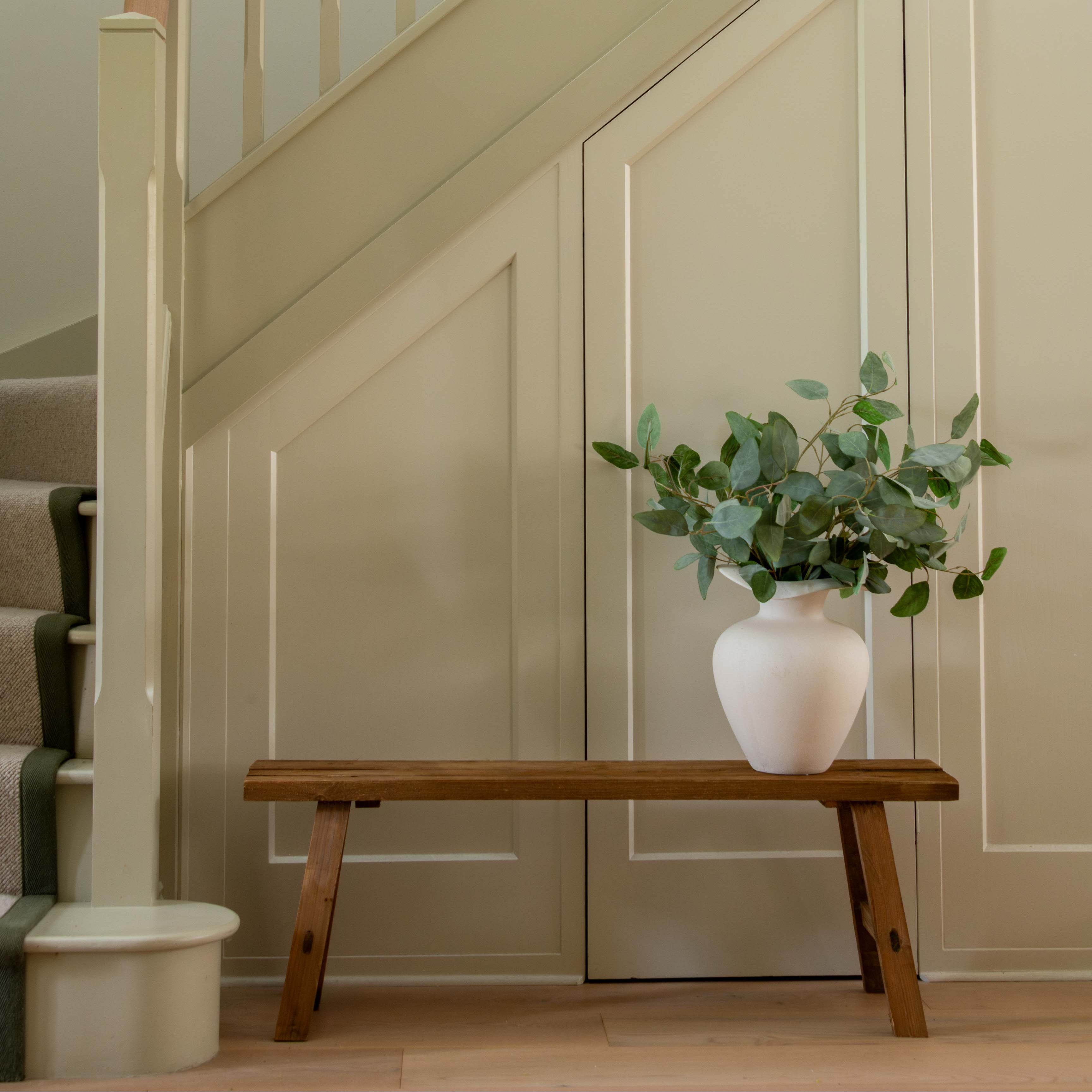 Staircase with a wooden bench and plant against a wall.