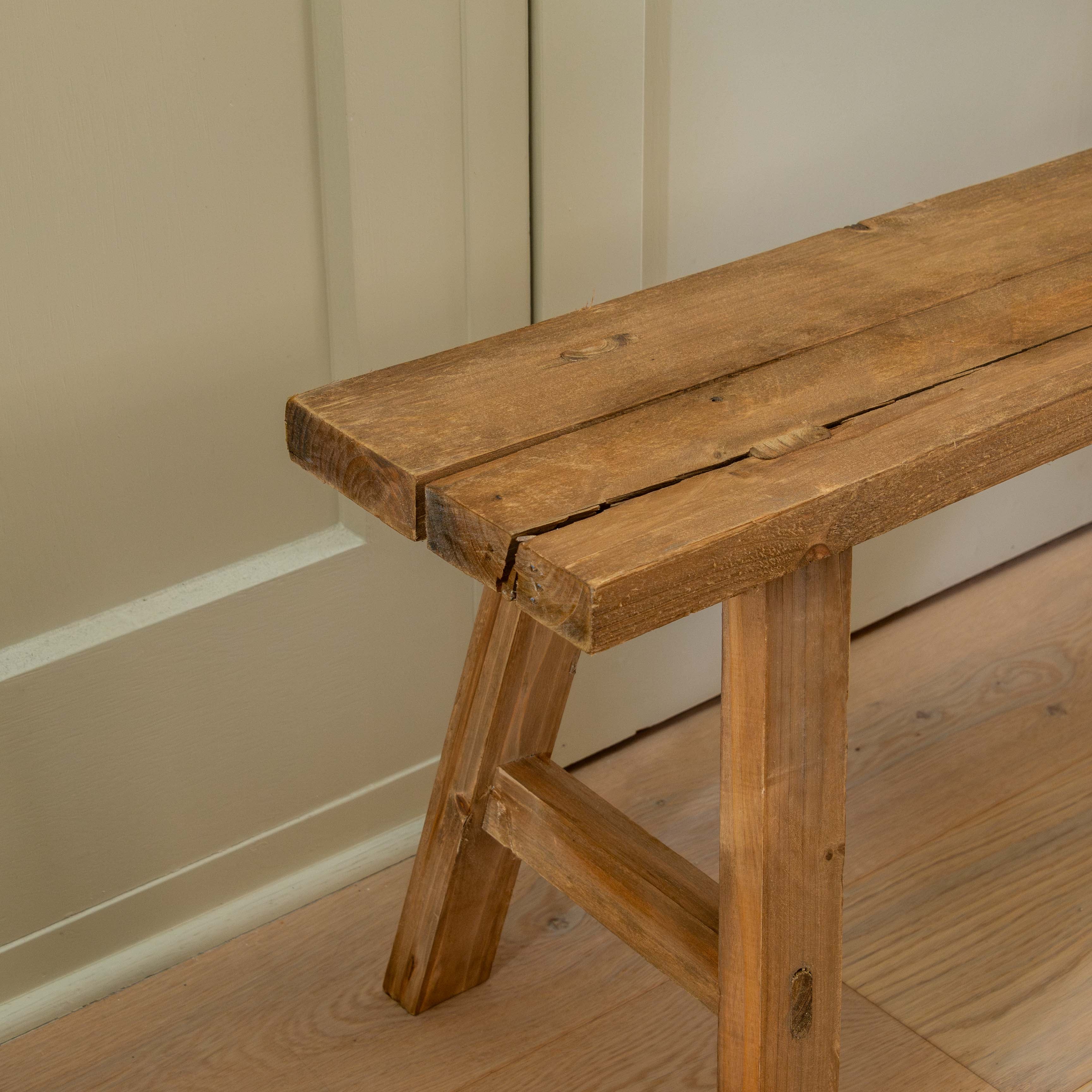 Wooden bench against a beige wall on a wooden floor