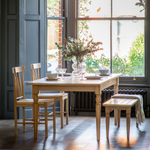 Bright dining space with Eton Oak Table, chairs, and bench near window